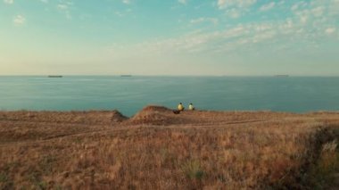 Uçurumun kenarında oturan ve Karadeniz 'i gören iki gezgin. Yuzhne, Odessa bölgesi, Ukrayna.