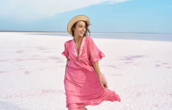 Kaunis onnellinen nainen emotionaalisesti hymyillä kameralle, yllään vaaleanpunainen mekko. Ukraina Sivash vaaleanpunainen järvi — kuvapankkivalokuva