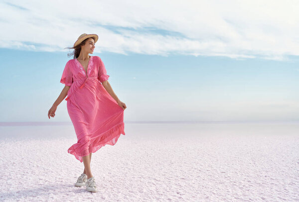 Adorable romantic woman admiring serenity colorful landscape of salt flats on pink lake Royalty Free Stock Images