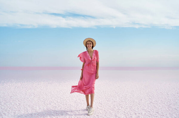 Panoramic beautiful landscape of salt flats on pink lake, girl in flowing pink dress enjoying walk Stock Photo