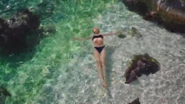 Siyah bikinili, turkuaz berrak deniz suyunda yüzen bir kadının havadan görünüşü. Türkiye 'de mutlu bir ada tatili, Akdeniz kıyısı. macera, seyahat