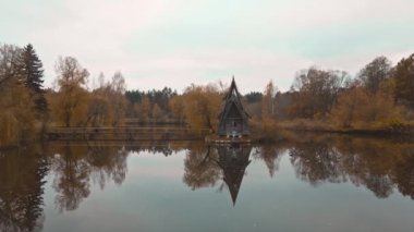 Panoramik hava görüntüleri, sonbahar manzarası, ormanın arasında göl kenarındaki ahşap ev, ahşap iskelede yürüyen kız. Suda yeşillik yansıması. Ukrayna 'da popüler turistik yerler