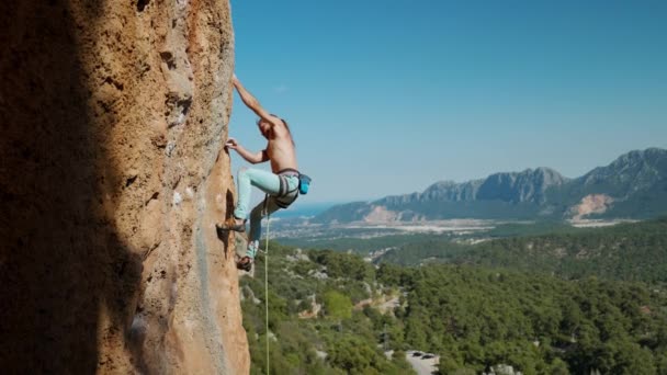 4K慢速运动的运动员用绳索爬上一块垂直的岩石 领先攀爬 山和蓝天背景上攀岩者的轮廓 户外运动和娱乐 — 图库视频影像