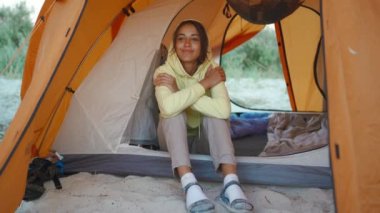 beautiful ukrainian Woman in orange camping tent admiring morning sunrise. Traveling camp lifestyle and alternative hotel room vacation concept. local traveling in Ukraine