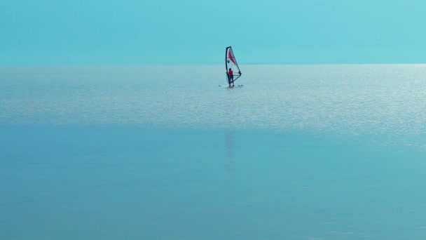 美しい夕日の空を背景に海上のウィンドサーフィンボードを航海するシルエットのウィンドサーファー 健康的なアクティブなライフスタイル 夏の楽しい冒険 — ストック動画