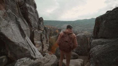 Sırt çantasıyla uçurumun kenarına kadar yürüyen kahverengi kıyafetli bir adam, popüler Tustan Milli Parkı, Ukrayna 'da güzel manzaralı dağ manzarasının tadını çıkarıyor. Macera, seyahat, doğa güzelliği