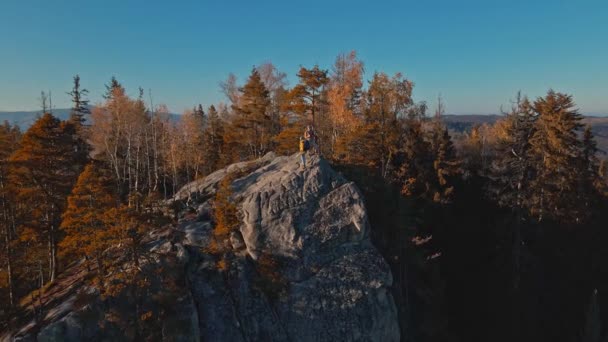 电影中的空中镜头是无人驾驶飞机飞越伍迪山脉悬崖顶上的一对远足夫妇 在乌克兰喀尔巴阡山脉欣赏美景的旅行者 日落时分 快乐的女孩和男人在一起 — 图库视频影像