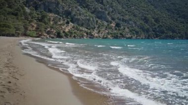 Güneşli yaz gününde dalgalarla dalgalanan deniz Türkiye 'nin güzel kumlu boş plajı Iztuzu' da. Arka planda güzel dağ sıraları