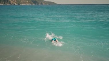 Dikiz görüşlü atletik adam Ege Denizi 'ndeki Oludeniz Sahili' nde turkuaz deniz suyuna dalıyor ve yüzüyor. Yaz Turisti Sezonu Fethiye, Mugla Türkiye