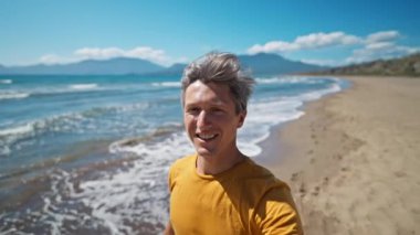 Deniz kıyısındaki mutlu orta yaşlı adamın selfie portresi Türkiye 'nin güzel kumlu plajı Iztuzu' da güneşli bir günün tadını çıkarıyor. İnsandan esinlenerek selfie videosu çeker ve el kamerasına el sallar