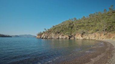 panoramic view of beautiful calm turquoise sea water at wild solitary pebble beach with cliffs at coast of mediterranean sea in Turkey. summer vacation, tourism and nature beauty