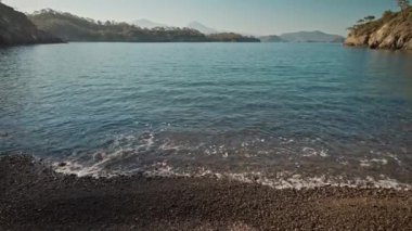 panoramic view of beautiful calm turquoise sea water at wild solitary pebble beach with cliffs at coast of mediterranean sea in Turkey. summer vacation, tourism and nature beauty