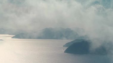 Türkiye 'de yüksek bir dağdan Ege Denizi' nin kayalık kıyılarına manzara. Yaz tatili ve Türkiye 'de seyahat. Sis ve bulutlar rüzgarla hareket eder