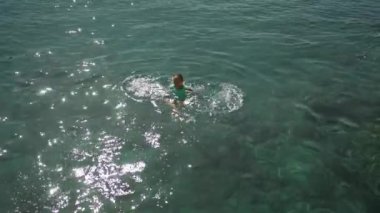 slow motion top view of sexy beautiful young woman in green swimsuit swimming on back and relaxing in clear turquoise water of mediterranean sea. vacation and wellness, Summer Season Fethiye, Turkey