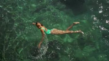 Akdeniz 'in berrak turkuaz sularında yüzen yeşil mayo giymiş seksi ve çarpıcı kadının yavaş çekim üst görüntüsü. tatil ve sağlık, Yaz Sezonu Fethiye, Türkiye