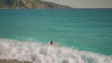 Mavi şortlu rahat yakışıklı sporcu yüzme ve güneş banyosu yaptıktan sonra Ege 'deki Oludeniz Sahili' nde Akdeniz 'in turkuaz sularında uzanarak eğleniyor. Yaz mevsimi Wibe