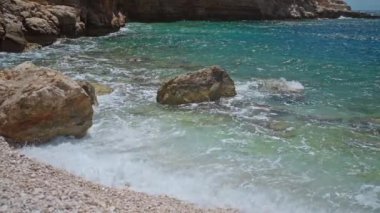slow motion footage tropical island and sea waves crashing and foaming against rocky beach. golden rocks coast meeting deep blue ocean water. Tourism in Turkey concept