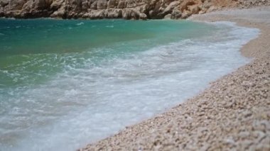 slow motion footage tropical island and sea waves crashing and foaming against pebble rocky beach. rocks coast meeting deep blue ocean water. Tourism in Turkey concept