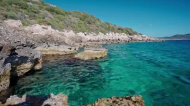 Türkiye 'nin Marmaris kentindeki kayalık kıyılarda Akdeniz' in berrak türkuaz sularının panoramik manzarası. Yaz mevsimi, turizm sezonu, güzel Türk tatil beldeleri.