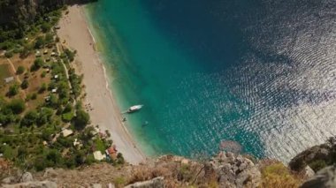 Kelebek Vadisi 'ndeki turkuaz mavi suların yukarıdan görünüşü güneşli bir yaz günü Fethiye Türkiye' de beyaz kumsalda demirli büyük turistik tekneler.