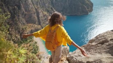4k slow motion happy traveler freedom filling woman with open arms smiling and enjoying sea coast view, summer journey vacation in Butterfly valley,Turkey. girl stands on top of cliff over sea