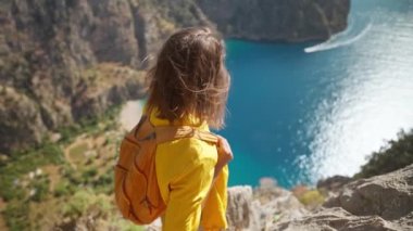 4k slow motion happy traveler freedom filling woman with open arms smiling and enjoying sea coast view, summer journey vacation in Butterfly valley,Turkey. girl stands on top of cliff over sea
