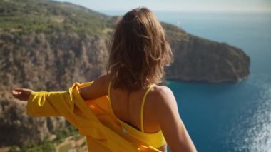 4k slow motion happy traveler freedom filling woman with open arms smiling and enjoying sea coast view, summer journey vacation in Butterfly valley,Turkey. girl stands on top of cliff over sea