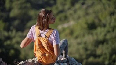 rear view girl hiker sits on edge of high cliff enjoying beautiful seascape of Aegean coastline mediterranean sea in Turkey from high mountain. Summer vacation and travel in Turkey. go everywhere