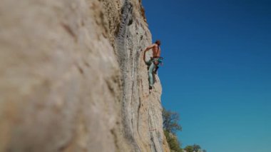 young powerful athletic man rock climber with long hair climbing on cliff. male climbing very hard route making long hard movement. extreme sport, rock climbing outdoors, training moments