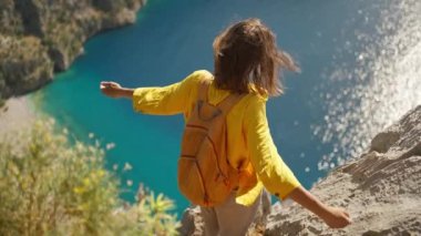 slow motion woman tourist with blowing hair enjoying sea coast view from high cliff over bay, summer journey vacation in Butterfly valley,Turkey. girl stands on top of cliff. go everywhere concept