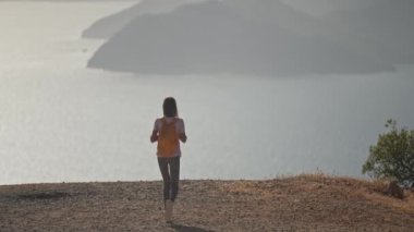 young woman tourist walks enjoying beautiful seascape of Aegean coastline mediterranean sea in Turkey from high mountain. Summer vacation and travel in Turkey. fog and clouds moves by wind