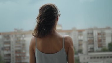 Evde balkonda duran genç bir kadının arkadan görünüşü, yavaş çekim, sosyal mesafeler ve karantina tecridi. Depresyon ve akıl hastalığı, intihar düşünceleri.