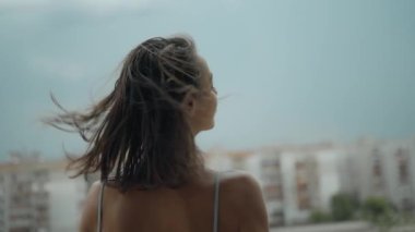 Arka planda, gecelikle balkonda duran genç bir kadın, arka planda dramatik bir gökyüzü. Depresif sahne, yüksekten atlamayı düşünen bir kız. Depresyon ve akıl hastalığı, intihar düşünceleri.