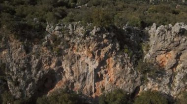 Güçlü kaya tırmanışçısının hava POV 'u Türkiye' de büyük tufayla dikey kireçtaşı uçurumunda zorlu kaya tırmanışı rotasına tırmandı. Tırmanışçı tırmanışı bitirdi, uçurumun tepesinde duruyor ve hazırlanıyor.