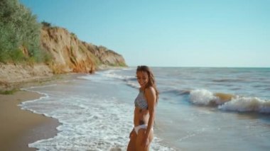 Bikinili seksi fitness kızının yüksek dikenli kil sahilde kumsalda yürüyüşünün yavaş çekim görüntüleri. seyahat tatili, ruh sağlığı, özgürlük ve sağlık kavramı.