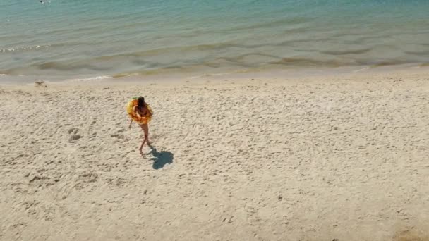 Аэросъемка Загорелой Женщины Ходящей Песчаному Пляжу Гигантским Плавающим Ананасовым Кольцом — стоковое видео
