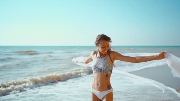 몸매의 소녀는 폭풍이 몰아칠 해변에서 파도를 즐기며 걷는다 비키니를 해변에서 — 비디오