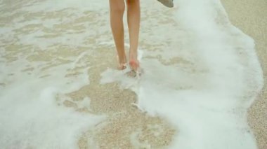 Arkaya bakan kadınlar ince bacaklar, kumlu sahilde tek başına yürüyen bir kız, rüzgarın, deniz dalgalarının ve bulutlu gökyüzünün tadını çıkarıyor. her yere git