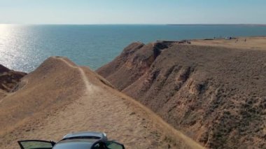 Araba yolculuğu konsepti. Hava aracı görüntüsü deniz kıyısındaki kil kanyonun kenarında.