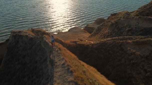 丘の上を走る空中幸せな女性ウェルシュ コーギー ドッグと日没時のパノラマビューで 自然の中で冒険を楽しむ美しい女の子 ウクライナのスタニスラフ渓谷 クリップにはノイズが — ストック動画