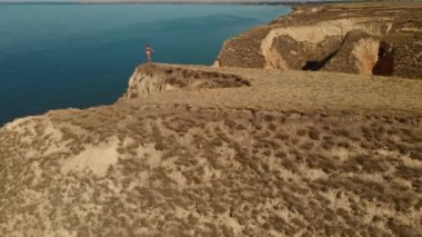 Hava manzaralı esneme egzersizleri. Fitness etrafında İHA uçuşları yapan kadın koşucu sabah egzersiz yapıyor ve deniz kıyısındaki kil tepe kanyonunda esniyor.