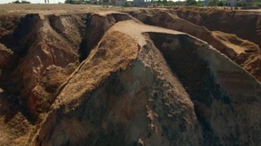 Dışarıdaki meditasyonun hava görüntüsü. Fitness etrafında İHA uçuşları yapan kadın sabahları deniz kıyısındaki kanyonun kil sırtında oturur ve egzersizlerden sonra meditasyon yapar.