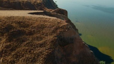 Dışarıdaki meditasyonun hava görüntüsü. Fitness etrafında İHA uçuşları yapan kadın sabahları deniz kıyısındaki kanyonun kil sırtında oturur ve egzersizlerden sonra meditasyon yapar.