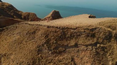 Sabahın erken saatlerinde deniz kıyısındaki güzel kil kanyon boyunca koşan kadın fitness koşucusunun hava yavaş çekim görüntüleri. Aktif boş zaman egzersizi yaz gündoğumunda. sağlıklı yaşam tarzı ve spor