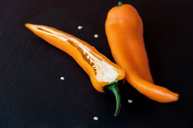 Bir tatlı portakallı biber ve yarısı koyu arkaplanda. Sağlıklı yaşam tarzı için olgun ve lezzetli ürünler. Seçici odaklanma. Boşluğu kopyala. Üst görünüm.