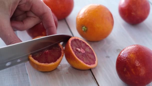 Mâinile femeilor au tăiat cuțitul copt suculent Portocale roșii cu sânge sicilian pe fundal din lemn. Fructe sezoniere. De aproape. Concept: fructe organice, alimente sănătoase. — Videoclip de stoc