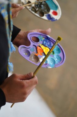 Ressamların ellerinde boyalar olan palet. Lastik eldivenli ve eldivensiz ama çalışmaya hazır..