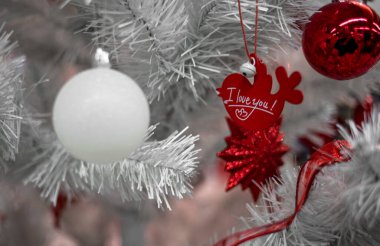 Güzel Noel kırmızı ve gümüşi toplar beyaz bir Noel ağacında. Kurdeleler şeklinde süslemeler ve yazıtlarla Mutlu Noeller ve mutlu yıllar.