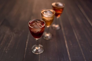 Ahşap bir masada cam yığınları içinde alkollü içecekler. Kiraz, fındık ve limon likörü..