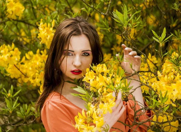 Young woman among yellow flowers — Stock Photo, Image